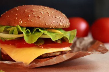 Delicious juicy burger with cutlet and fresh ingredients. Delicious cheeseburger. Fast food on a dark background, close-up