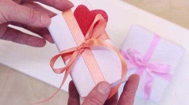 Gift for Valentine's Day, birthday or Mother's Day. White box with ribbon bow. Gift in hand, close up