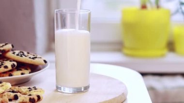 Pour milk into a glass. A glass of milk and delicious chocolate chip cookies. Natural source of calcium