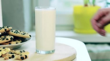 A woman's hand takes a glass of milk. A glass of milk and delicious chocolate chip cookies. Healthy lifestyle. Breakfast in the kitchen