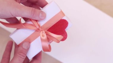 Gift for Valentine's Day, birthday or Mother's Day. White box with ribbon bow. Gift in hand, close up