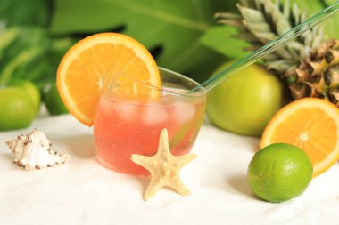 Bardakta portakal dilimi olan alkollü bir içecek. Olgun meyvelerin arka planında ferahlatıcı içecek. Tatil, yaz, tatil, lüks tatil beldesi konsepti. Seçici odak