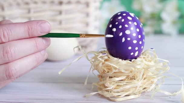用刷子刷复活节彩蛋 然后涂上白点 鸡蛋在一个小鸟巢的背景下 一个模糊的篮子 复活节的组成 筹备节日 基督教传统 — 图库视频影像