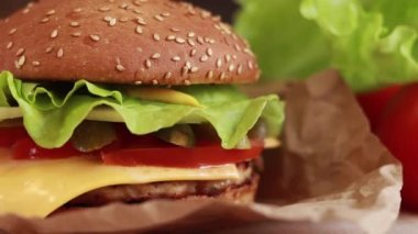 Homemade juicy cheeseburger close-up. Burger with cheese, cutlet, fresh lettuce and tomatoes