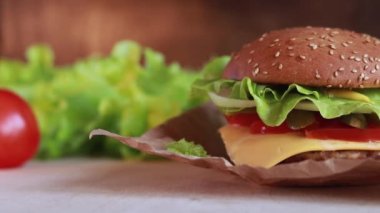 Homemade juicy cheeseburger close-up. Burger with cheese, cutlet, fresh lettuce and tomatoes