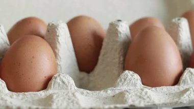Chicken eggs in a cardboard box. Fresh raw eggs in a paper egg container. A woman's hand puts an egg in a package