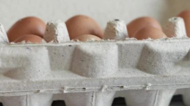 A woman's hand takes an egg from a cardboard box. Fresh raw eggs in a paper egg container. Opening the egg pack, close up. Fresh Protein Food