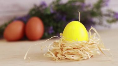 Yellow Easter egg in a nest on a background of flowers. Christ is risen. Easter holiday