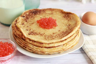 Pancakes with red caviar close-up on the background of the festive table. A stack of hot pancakes. Maslenitsa, Shrovetide. Pancake week