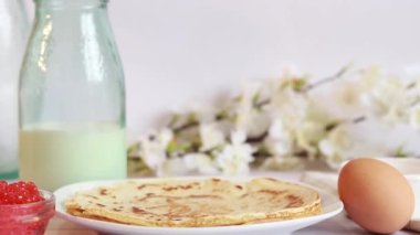 Preparation of thin pancakes, still life. Put the pancake on the stack. Breakfast in a cozy kitchen