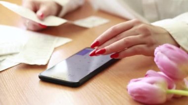 Finansal harcamaları hesaplayan, çekleri takip eden, aile bütçesini yöneten bir kadın. Kadın eli ve telefonda bir hesap makinesi. Kız satın alma miktarını hesaplıyor.