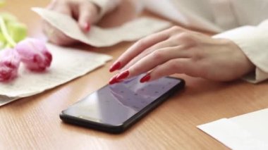 Muhasebecilik. Kadın eli ve akıllı telefondan hesap makinesi, harcamaları takip et. Toplam satın alma miktarını hesapla