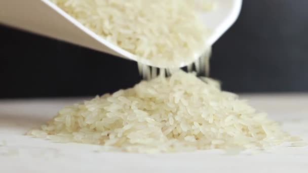 米粒从塑料白色勺子中溢出 煮熟了很久的米饭 稻谷在黑色的背景上堆成一堆 — 图库视频影像