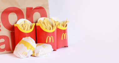 Kyiv, Ukrayna - 22 Mart 2023: Hafif bir arka plan ve kese kağıdında birkaç paket patates kızartması ve çizburger. McDonald 's Corporation dünyanın en büyük fast food restoranıdır.