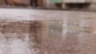 Kaldırımda yağmur ve su birikintileri. Sonbahar ya da bahar yağmuru. Dışarıda yağmur, zemin kattan görüntüler. Islak asfalt