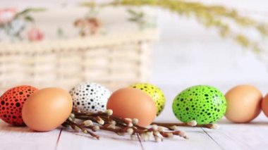Paskalya yumurtaları ahşap bir masa ve söğüt dalları üzerinde. Boyalı Paskalya yumurtaları dini bayramın geleneksel bir sembolüdür. Hristiyan kutlama gelenekleri