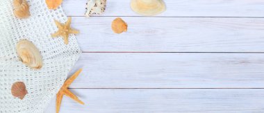 Kum, deniz kabuğu ve deniz yıldızından oluşan açık ahşap bir arka plan. Yaz kompozisyonu, tahta arka planı ve kum. Yaz tatili konsepti.