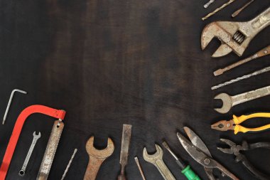 Düz kompozisyon ve eski aletler koyu ahşap arka planda. Çeşitli tamir araçlarıyla üst görünüm. Araçlar ve boş alan
