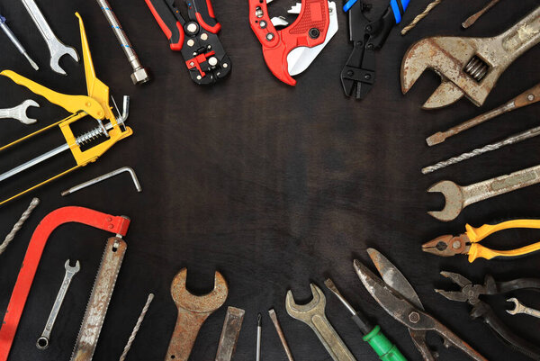 Flat lay composition with old and new instruments on a dark wooden background. Top view with various repair tools. Tools and empty space for text