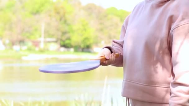 那个选手拿着网球拍 在自然界中等待游戏 木制网球拍和手球 湖边的户外运动 — 图库视频影像