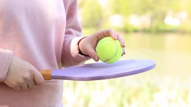 選手はテニスラケットを持っている 自然の中でゲームを待っている 木製のテニスラケットとボールを手に入れました 湖の近くの屋外ゲーム — ストック動画