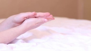 Kız, kremi cilde çarşafın arka planına sürmüş. Yaşlanma önleyici cilt bakım ürünleri. Eller yakın çekim, kız nemlendirici sürüyor ve yumuşaklık için eline masaj yapıyor.