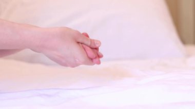 Kız, kremi cilde çarşafın arka planına sürmüş. Yaşlanma önleyici cilt bakım ürünleri. Eller yakın çekim, kız nemlendirici sürüyor ve yumuşaklık için eline masaj yapıyor.