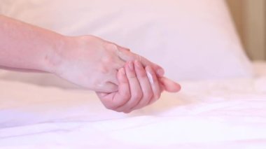Kız, kremi cilde çarşafın arka planına sürmüş. Yaşlanma önleyici cilt bakım ürünleri. Eller yakın çekim, kız nemlendirici sürüyor ve yumuşaklık için eline masaj yapıyor.