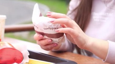 Kyiv, Ukrayna - 11 Mayıs 2023: McDonald 's' dan fast food. Elleri hamburgerle yakın plan. Hamburgeri paketten çıkar