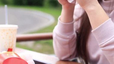 Kyiv, Ukrayna - 11 Mayıs 2023: Kız bir McDonald 's hamburgeri yiyor. Fast food restoranında hamburger yiyen bir kadın. McDonald 's Corporation dünyanın en büyük fast food restoranıdır. Açık hava masasında yemek. Seçici odak