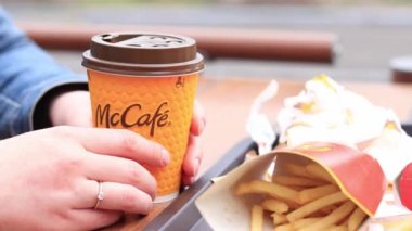 Kyiv, Ukrayna - 11 Mayıs 2023: McDonald 's' dan fast food. Kahve ve patates kızartmasıyla yakın plan kadın eli. Açık hava masasında yemek. Seçici odak