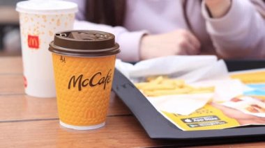 Kyiv, Ukrayna - 11 Mayıs 2023: Kız McDonalds 'da açık hava masasında yemek yiyor. Kız fast food yiyor. Kadın eli patates kızartması alır. McDonald 's Şirketi