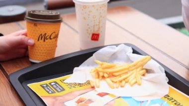 Kyiv, Ukrayna - 11 Mayıs 2023: McDonald 's' dan fast food. McDonalds 'dan gelen yiyeceklerle insanların ellerini yakın plan çekiyoruz. Güneşli bir günde açık bir masada yemek yemek.