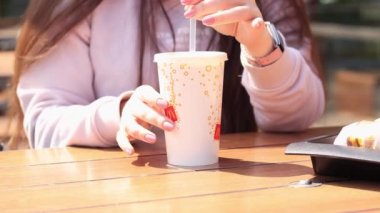 Kyiv, Ukrayna - 11 Mayıs 2023: McDonald 's' dan fast food. Güneşli bir günde açık havada bir masada otururken bir kız Coca Cola içer.