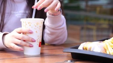 Kyiv, Ukrayna - 11 Mayıs 2023: McDonald 's' dan fast food. Güneşli bir günde açık havada bir masada otururken bir kız Coca Cola içer.