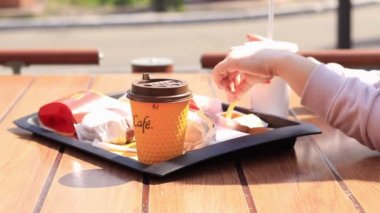 Kyiv, Ukrayna - 11 Mayıs 2023: Kız McDonalds 'da açık hava masasında yemek yiyor. Kız fast food yiyor. Kadın eli patates kızartması alır. McDonald 's Corporation dünyanın en büyük fast food restoranıdır.