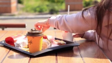 Kyiv, Ukrayna - 11 Mayıs 2023: Kız McDonalds 'da açık hava masasında yemek yiyor. Kız fast food yiyor. Kadın eli patates kızartması alır. McDonald 's Corporation dünyanın en büyük fast food restoranıdır.