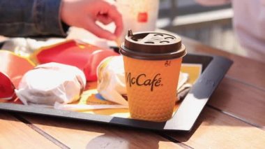 Kyiv, Ukrayna - 11 Mayıs 2023: Kız McDonalds 'da açık hava masasında yemek yiyor. Kız fast food yiyor. Kadın eli patates kızartması alır. McDonald 's Corporation dünyanın en büyük fast food restoranıdır.