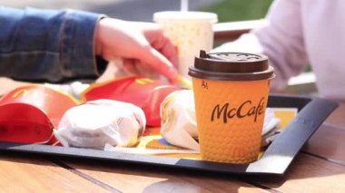 Kyiv, Ukrayna - 11 Mayıs 2023: Kız McDonalds 'da açık hava masasında yemek yiyor. Kız fast food yiyor. Kadın eli patates kızartması alır. McDonald 's Corporation dünyanın en büyük fast food restoranıdır.