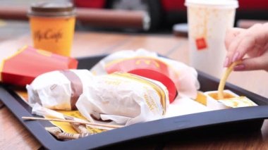 Kyiv, Ukrayna - 11 Mayıs 2023: Kız McDonalds 'da açık hava masasında yemek yiyor. Kız fast food yiyor. Kadın eli patates kızartması alır. McDonald 's Corporation dünyanın en büyük fast food restoranıdır.