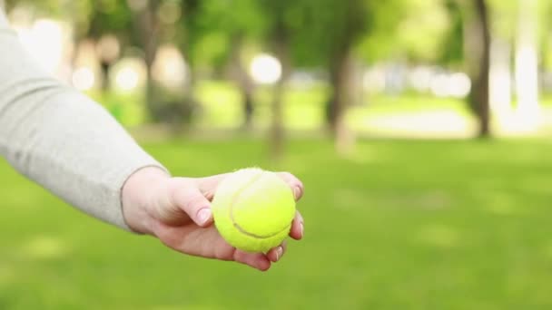 新鮮な空気の中でテニスをするための緑のボールと明るいラケット 天気の良い日に趣味やレクリエーション 女性の手は木製のラケットのクローズアップでボールを打つ — ストック動画