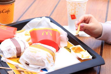 Kyiv, Ukrayna - 11 Mayıs 2023: Kız McDonalds 'da açık hava masasında yemek yiyor. Kız fast food yiyor. Kadın eli patates kızartması alır. McDonald 's Şirketi