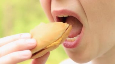 Kız fast food restoranından bir çizburger yiyor. Yakın plan bir burger ısır. Lezzetli fast food, zevkle fast food yiyin. Bir kadın iştah açıcı bir şekilde hamburger yer.