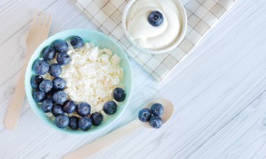 Sağlıklı kahvaltı. Yaban mersinli süzme peynir, en iyi manzara. Sağlıklı keto kahvaltı konsepti, taze böğürtlen ve ekşi kremalı süzme peynir. Sağlıklı kahvaltı tabağı, tahta kaşık ve çatal.