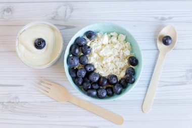 Yabanmersinli süzme peynir, taze böğürtlen, keto sağlıklı kahvaltı konsepti, üst manzara. Sağlıklı kahvaltı tabağı, tahta kaşık ve çatal.