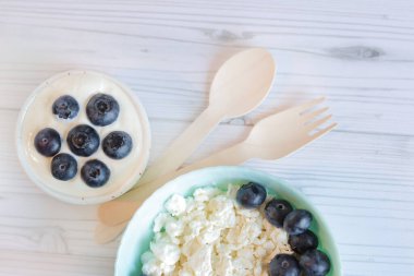 Sağlıklı kahvaltı. Yaban mersinli süzme peynir, en iyi manzara. Sağlıklı keto kahvaltı konsepti, taze böğürtlen ve ekşi kremalı süzme peynir. Sağlıklı kahvaltı tabağı, tahta kaşık ve çatal.
