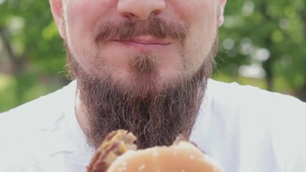 Eet Een Hamburger Een Close Mannelijk Gezicht Die Een Cheeseburger — Stockvideo
