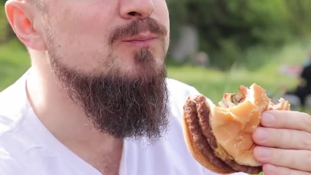 Eet Een Hamburger Een Close Mannelijk Gezicht Die Een Cheeseburger — Stockvideo