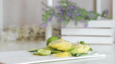 Ev yapımı mojito veya limonata. Bir kadının eli plastik bardağı serin bir yaz içeceğinin yanına koyar. Parlak bir mutfakta serinletici bir içeceği olan plastik bir bardak.