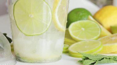 Ev yapımı mojito yapıyorum. Plastik bardağa soda ya da maden suyu dökün. Buzlu, limonlu, limonlu ve naneli bir bardağın yakın çekimi. Limonata hazırlığı
